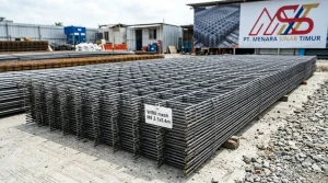 Tumpukan lembaran wiremesh baja dengan anyaman kotak-kotak tersusun mendatar di area lokasi proyek konstruksi